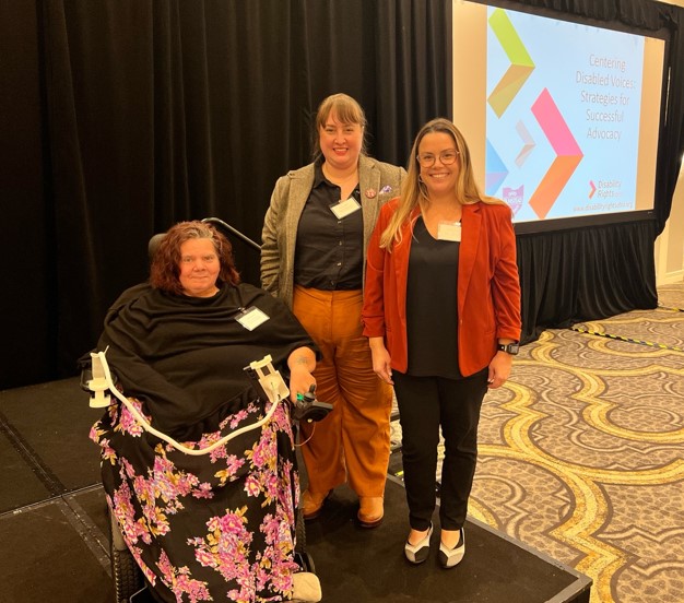 Photo of conference attendees with presentation screen in background.