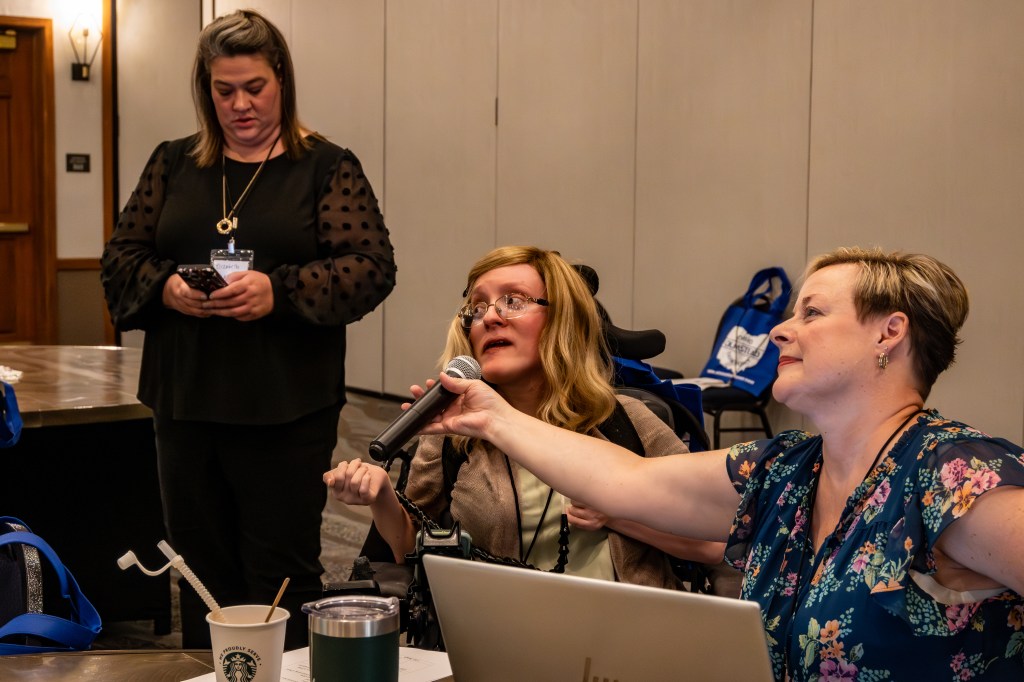 OOTF advocate addresses group at retreat while someone holds the mic to her mouth.