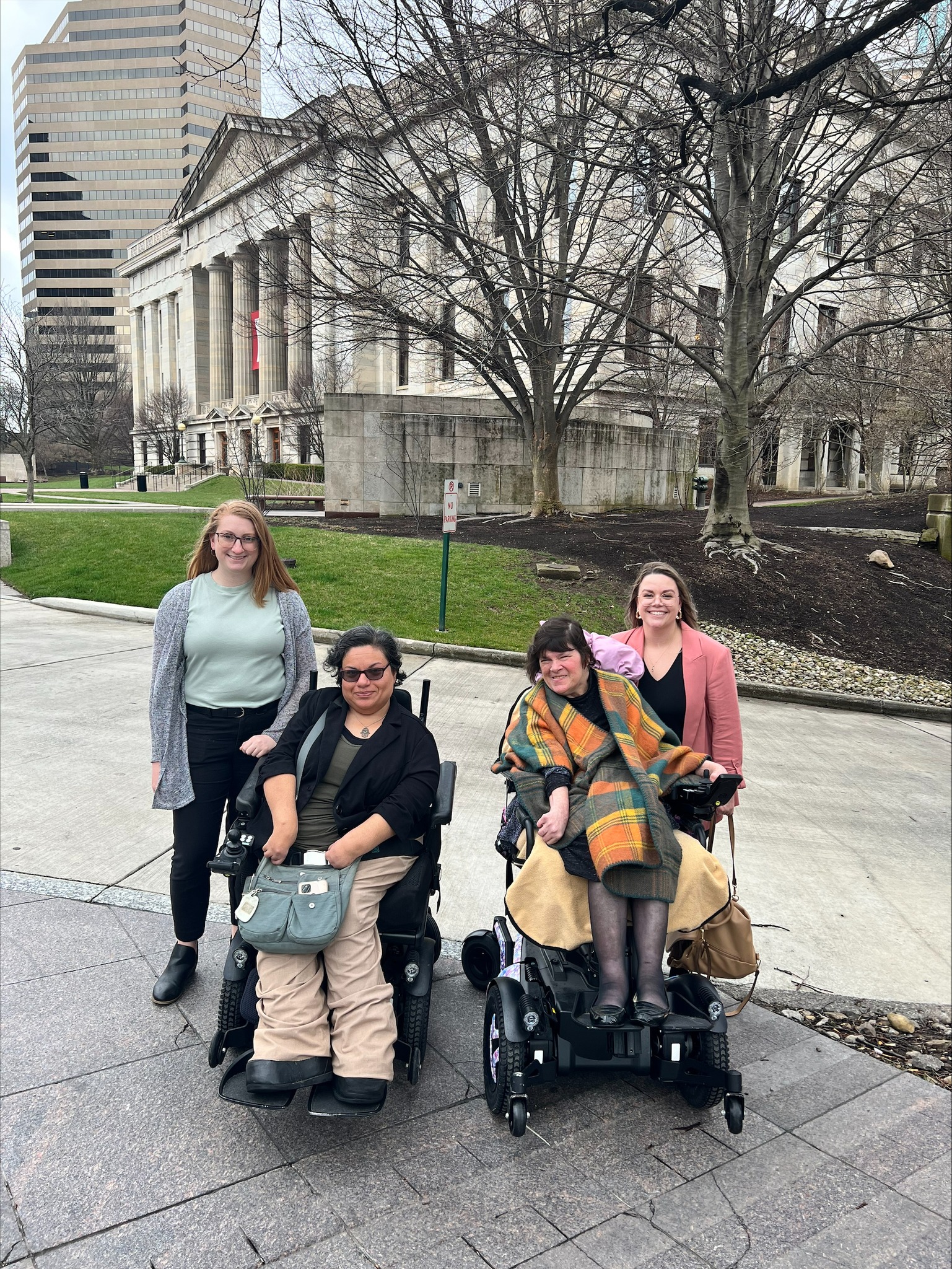 Four OOTF advocates sitting and standing outside the statehouse in DC.